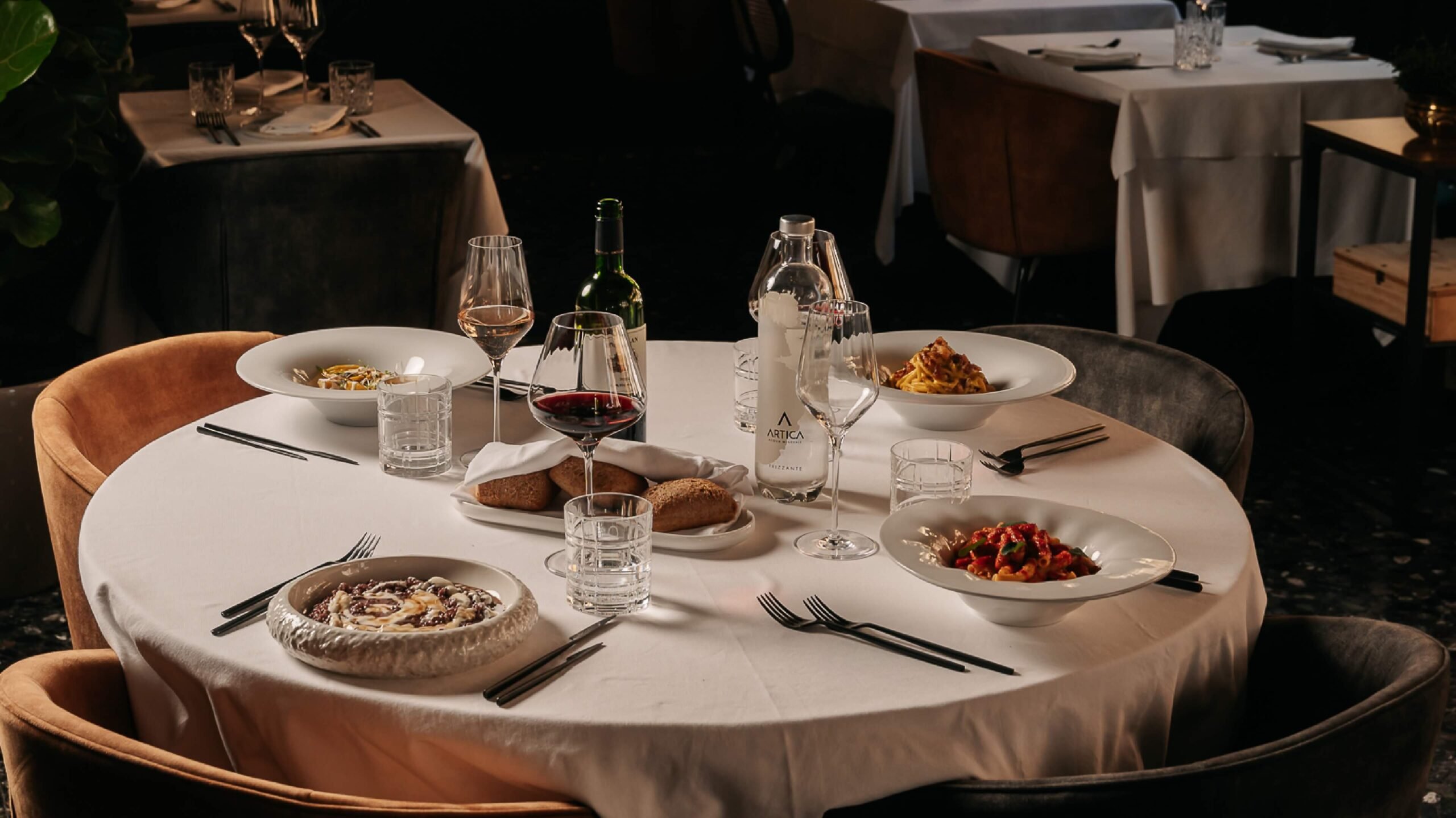 Tavolo rotondo con piatti tipici e vino rosso al ristorante I Morosetti Verona